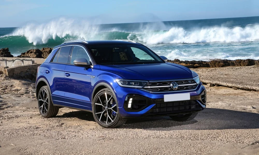 Фото Volkswagen T-Roc — вид спереди, фото 6. Синий кузов, строгая симметрия оптики — базовый ракурс знакомства с дизайном. Рисунок ходовых огней — подпись модели, по нему её узнают в потоке Volkswagen T-Roc — вид спереди, фото 6