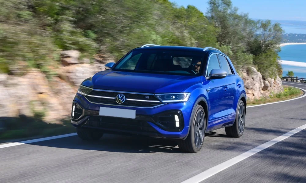 Фото Volkswagen T-Roc — вид спереди, фото 7. Передок в синем исполнении — крупная светотехника и выразительный бампер. Рисунок ходовых огней — подпись модели, по нему её узнают в потоке Volkswagen T-Roc — вид спереди, фото 7