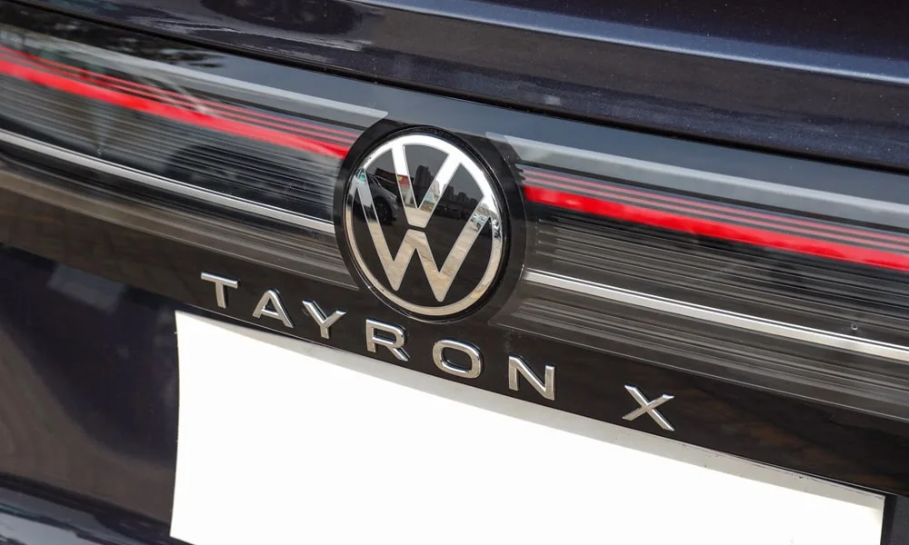 Фото Volkswagen Tayron X — эмблема. Логотип марки крупным планом. Шильдик версии на корме помогает отличать комплектации Volkswagen Tayron X — эмблема