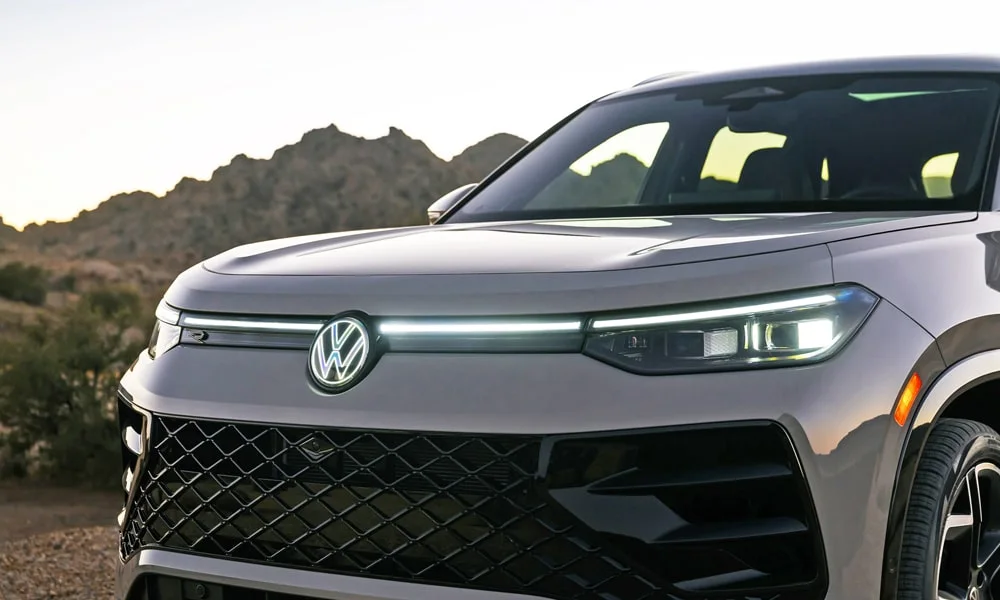 Фото Volkswagen Tiguan (2024) — вид спереди, фото 6. Серый кузов, строгая симметрия оптики — базовый ракурс знакомства с дизайном. Рисунок ходовых огней — подпись модели, по нему её узнают в потоке Volkswagen Tiguan (2024) — вид спереди, фото 6