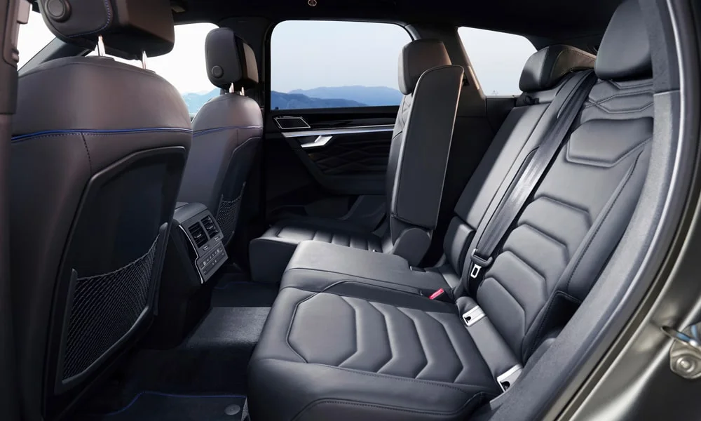 Фото Volkswagen Touareg (2024) — задние сиденья, фото 4. Посадка второго ряда: подголовники и подлокотник. Плоский пол упрощает посадку втроём Volkswagen Touareg (2024) — задние сиденья, фото 4