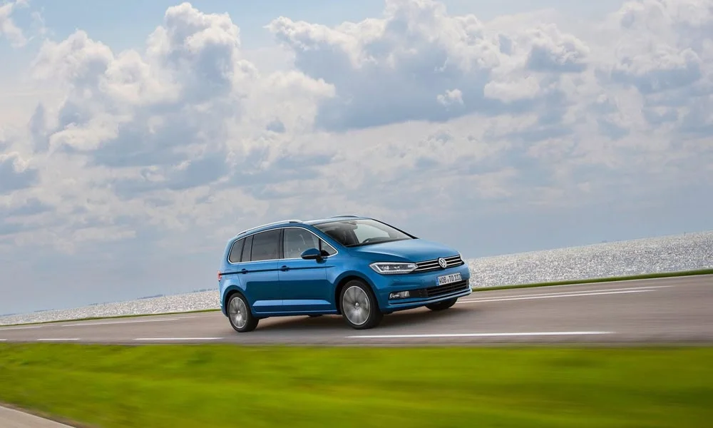 Фото Volkswagen Touran — вид спереди, фото 4. Кузов в синем цвете: рисунок оптики и решётки задаёт узнаваемое «лицо» модели. Дневные ходовые огни включаются автоматически с запуском Volkswagen Touran — вид спереди, фото 4